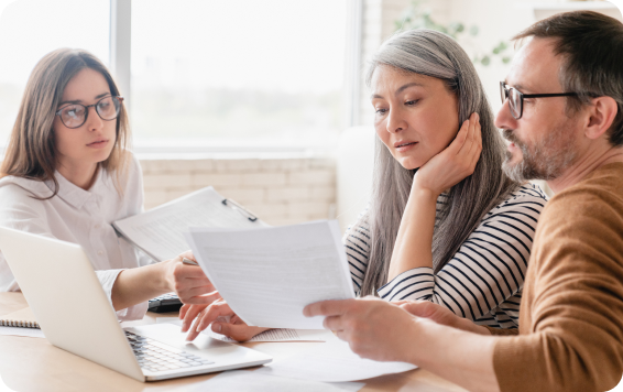 Three people reviewing documents at a desk.