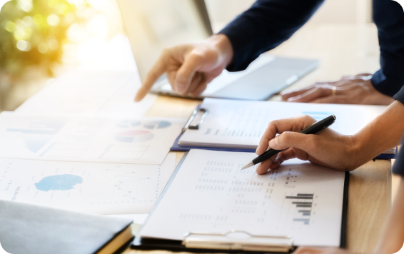 Businesspeople analyzing data with pen and charts.