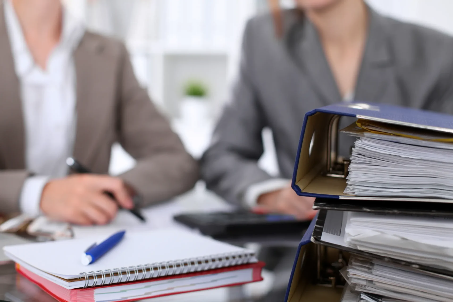 Stacked office binders on a desk.