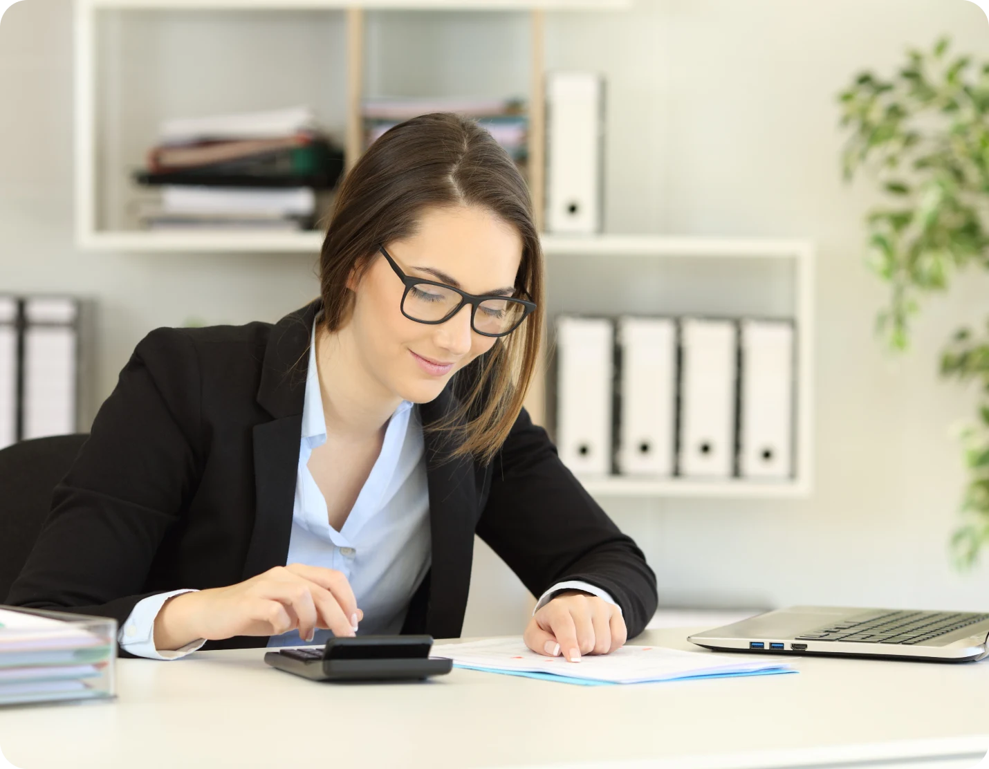 Businesswoman using calculator at desk.