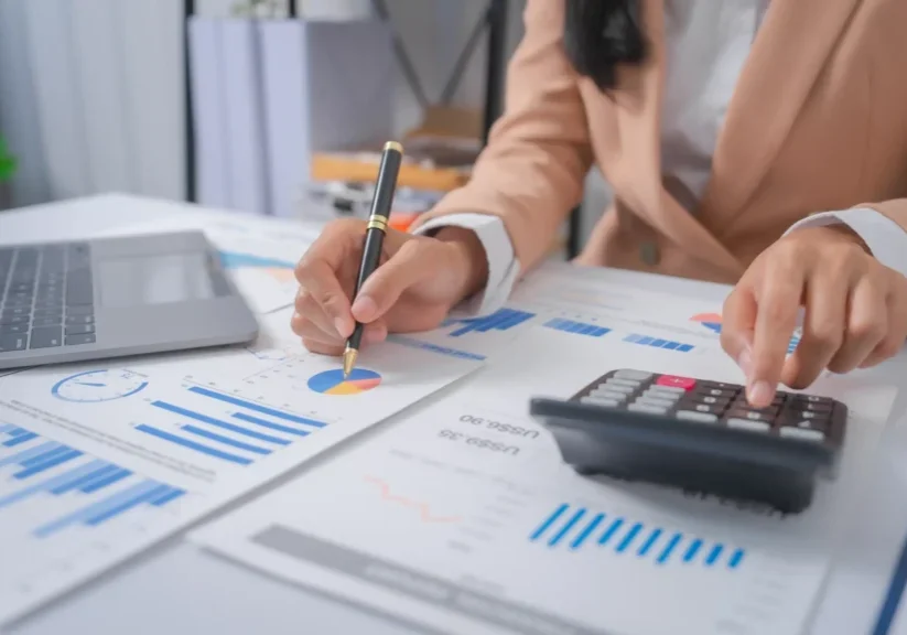 Woman analyzing financial data with calculator.